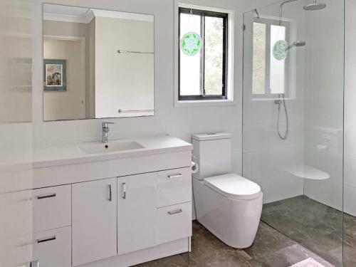 a white bathroom with a toilet and a sink at Quiet Private Nimbin Townhouse in Nimbin