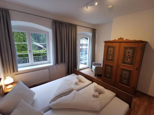 a bedroom with a large white bed and two windows at Apartments HAUS SCHÖN - Preise inclusive Pitztal Sommer Card in Jerzens