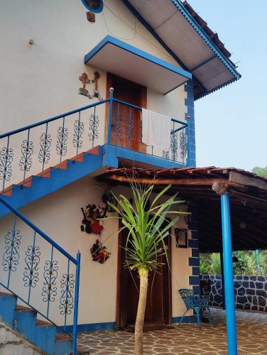 a house with a blue staircase and a palm tree at Aqua Arina Holiday Farm House in Murud