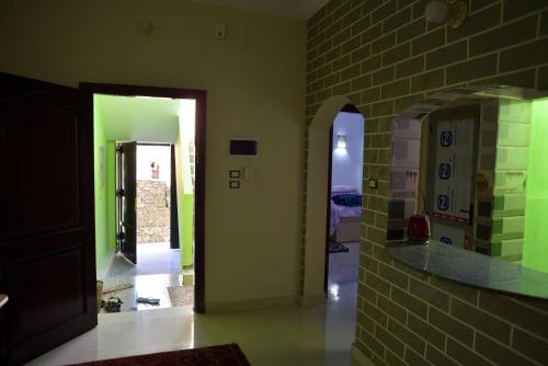 a hallway with green walls and a brick wall at Nubian Queen Guest House in Aswan