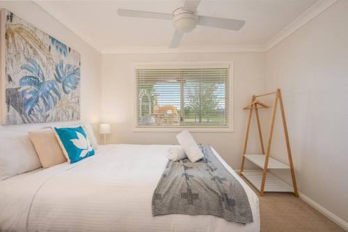 Schlafzimmer mit einem großen weißen Bett und einem Fenster in der Unterkunft 'Vineyard Cottage' A Golden Escape among the Vines in Eurunderee