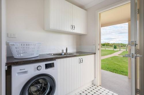 a kitchen with a washing machine and a sink at 'Vineyard Cottage' A Golden Escape among the Vines in Mudgee