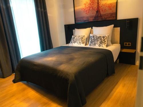 Un dormitorio con una gran cama negra con almohadas en Appartement Neuf- Morangis-Orly, en Morangis