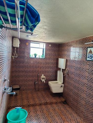 a tiled bathroom with a toilet and a window at Aqua Arina Holiday Farm House in Murud