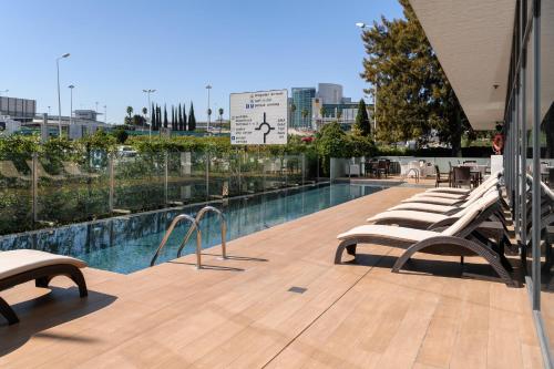 - une rangée de chaises longues à côté de la piscine dans l'établissement Meliá Lisboa Aeroporto, à Lisbonne