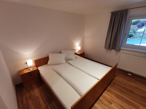 a bed in a room with two lamps on tables at Apartments HAUS SCHÖN - Preise inclusive Pitztal Sommer Card in Jerzens