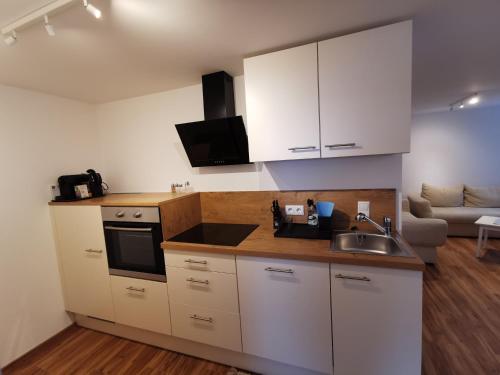 a kitchen with white cabinets and a sink and a couch at Apartments HAUS SCHÖN - Preise inclusive Pitztal Sommer Card in Jerzens