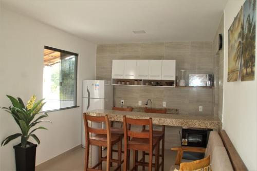 a kitchen with a table and chairs and a refrigerator at Residencial Jardim Imbassai 4 apt mobiliado com piscina in Mata de Sao Joao