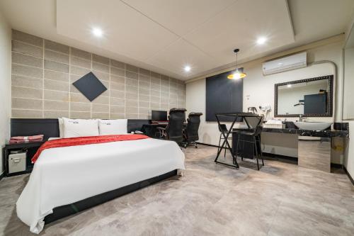 a bedroom with a bed and a desk and a television at Boutique Hotel XYM in Suwon