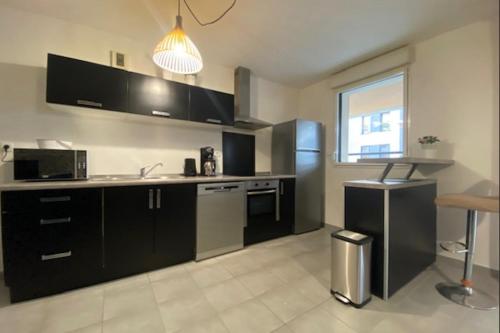 une cuisine avec des armoires noires et un réfrigérateur en acier inoxydable dans l'établissement Cosy apartment with balcony in the heart of Caen, à Caen