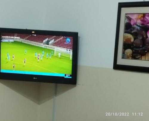 a television on a wall with a soccer game on it at Al Basateen Hotel Apartment in Sur