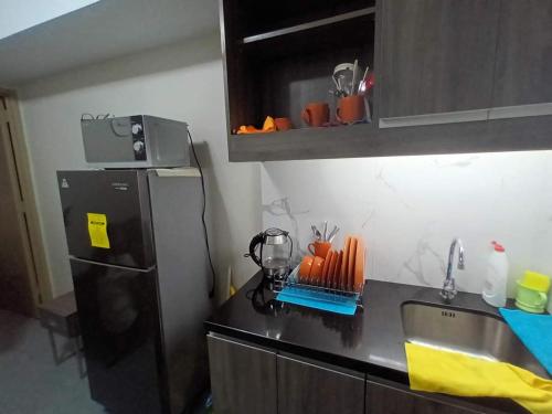La cuisine est équipée d'un réfrigérateur noir et d'un évier. dans l'établissement Sobere Unit, à Manille