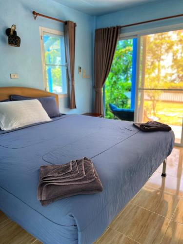 a blue bed with a towel on top of it at Twocans Homestay KohMak - SHA in Ko Mak