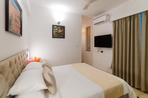 a hotel room with a bed and a television at Lotus & Orchid Villas by Ramnath Homes in Sangolda