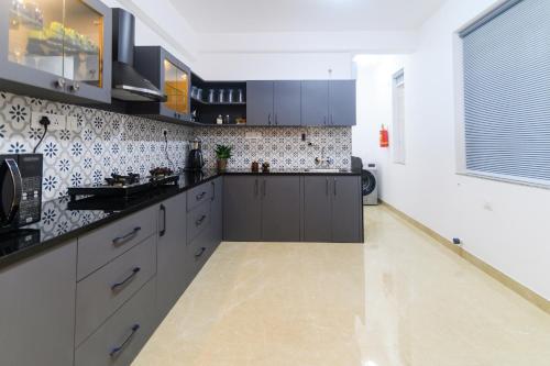 a kitchen with gray cabinets and a tile wall at Lotus & Orchid Villas by Ramnath Homes in Sangolda