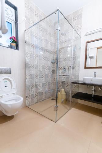 a bathroom with a glass shower stall and a toilet at Lotus & Orchid Villas by Ramnath Homes in Sangolda