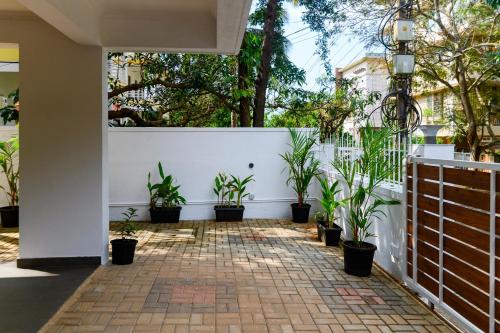 a courtyard with potted plants in front of a white fence at Lotus & Orchid Villas by Ramnath Homes in Sangolda