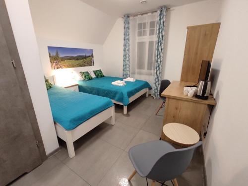 a room with two beds and a desk and a television at WILLA DobraNocka in Szklarska Poręba