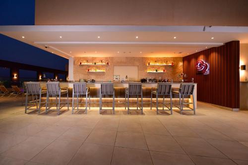 a bar in a restaurant with chairs and a counter at Clarion Hotel Jeddah Airport in Jeddah