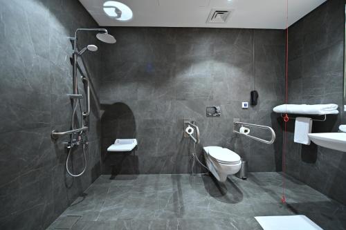 a bathroom with a shower and a toilet and a sink at Clarion Hotel Jeddah Airport in Jeddah