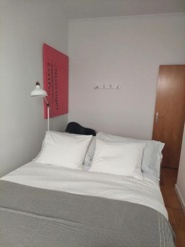 a bed with white pillows and a red sign on the wall at GALLE - Apartamento dos Infantes in Beja