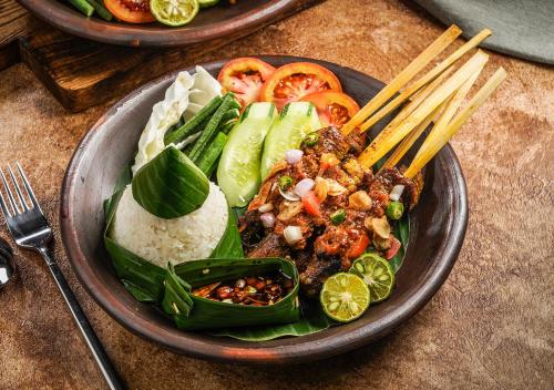 a plate of food with vegetables and rice and chopsticks at AYANA Midplaza JAKARTA in Jakarta