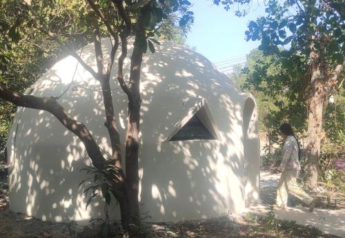 uma pessoa em frente a uma casa em forma de cúpula branca em Done Right em Phumĭ Chroŭy Svay