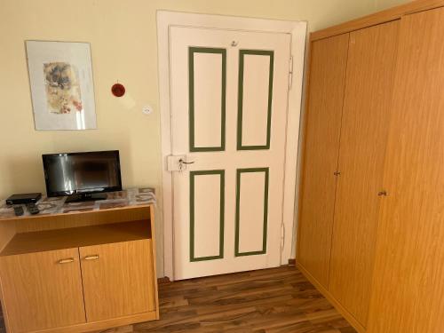 a room with a door with a television and a desk at Gästehaus Gut Frauendorf in Windorf