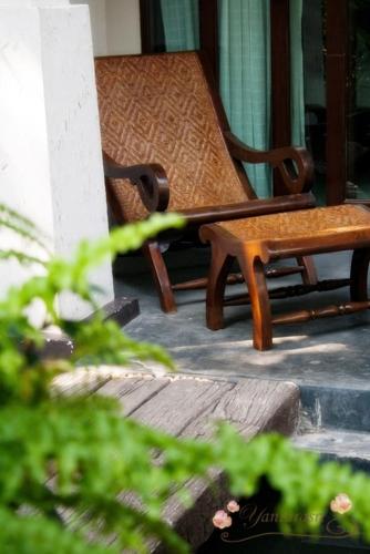 a bench and a chair on a porch at Yantarasri Resort in Chiang Mai