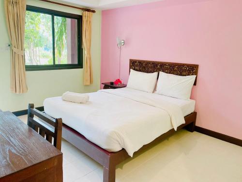 a bedroom with a large bed with a pink wall at Baan Karnjana Hotel Samui in Lamai