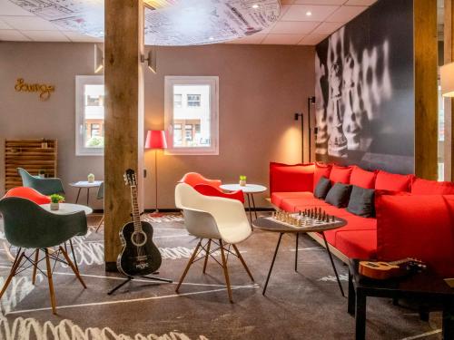 a living room with a red couch and a guitar at ibis Gap Centre in Gap