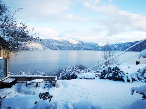 a picnic table in the snow next to a lake at Stranda apartment in Stranda