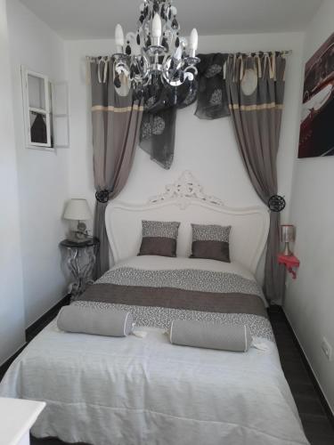 sypialnia z dużym łóżkiem i żyrandolem w obiekcie Residence Hotel de la Plage w mieście Saint-Gilles-Croix-de-Vie