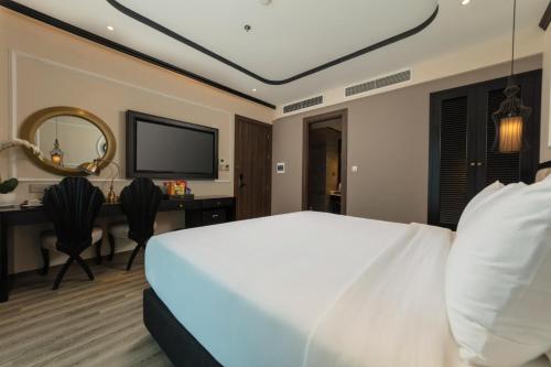 a bedroom with a bed and a desk and a television at FTE Ba Dinh Hotel in Hanoi