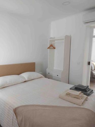 a bedroom with a white bed with a robe on it at Casa Maria Inácia T2 in Évora