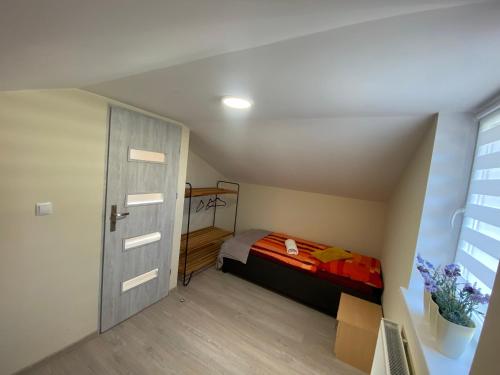 a small attic bedroom with a bed and a door at Domek ADA in Karpacz