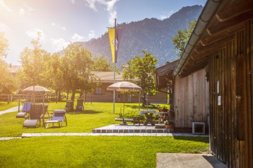 a yard with chairs and umbrellas and a building at Der Anderlbauer am See in Schliersee