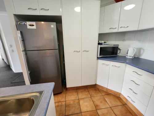 a kitchen with a stainless steel refrigerator and white cabinets at Fairways Golf & Beach Retreat Bribie Island in Woorim