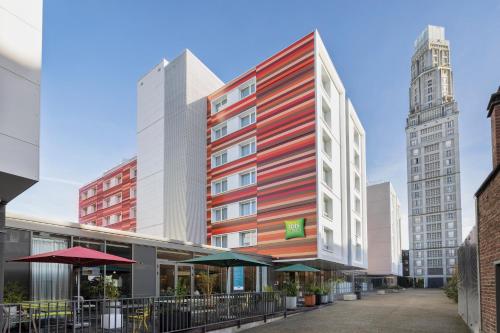 a red and white building in a city with tall buildings at ibis Styles Amiens Centre in Amiens