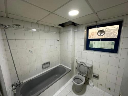 a bathroom with a tub and a toilet and a window at Low Priced New Residential Rooms for Men Guests near DAFZA Metro Station in Dubai