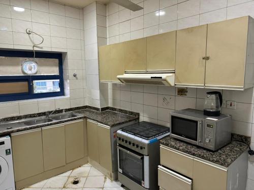 a small kitchen with a stove and a microwave at Low Priced New Residential Rooms for Men Guests near DAFZA Metro Station in Dubai