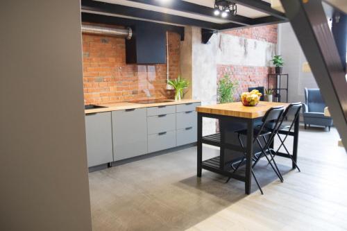a kitchen with a table and a brick wall at RedCity LOFT 309 in Żyrardów