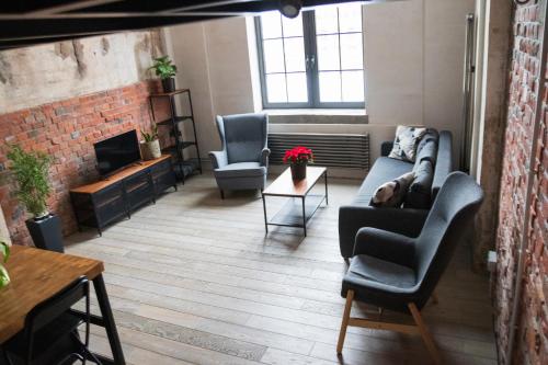 ein Wohnzimmer mit einem Sofa, Stühlen und einem Kamin in der Unterkunft RedCity LOFT 309 in Żyrardów