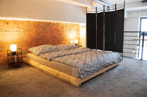 a bedroom with a large bed with a brick wall at RedCity LOFT 309 in Żyrardów