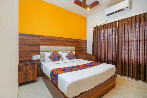 a bedroom with a bed and a yellow wall at FabHotel Greenwood Xpress Inn - Nr Manipal Hospital in Bengaluru