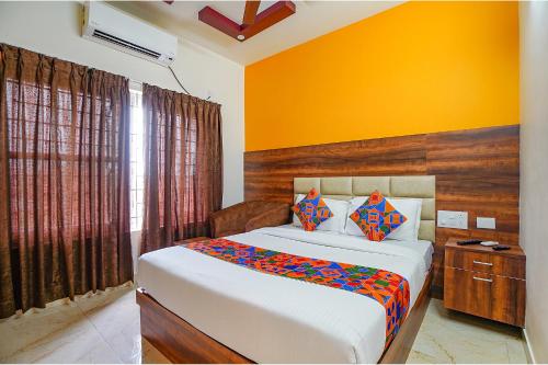 a bedroom with a bed and a yellow wall at FabHotel Greenwood Xpress Inn - Nr Manipal Hospital in Bengaluru