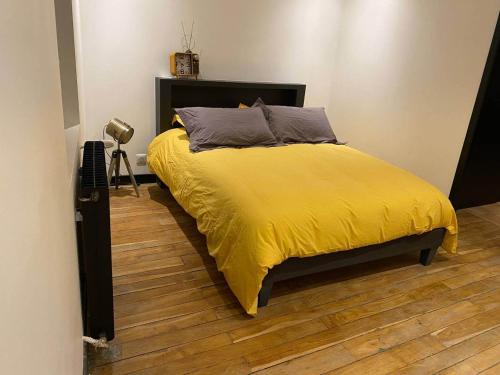 - une chambre avec un lit et une couverture jaune dans l'établissement CAPUCINE, à Bourges