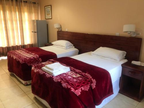 a hotel room with two beds with red sheets at A boutique lodge situated in a serene environment - 2029 in Harare