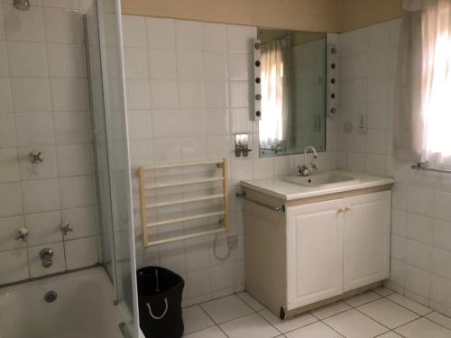 uma casa de banho com um lavatório, um chuveiro e um espelho. em A boutique lodge situated in a serene environment - 2021 em Harare