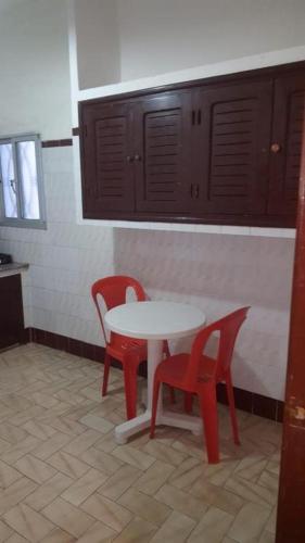 a kitchen with a table and two red chairs at Residence Mediterranee in Martil
